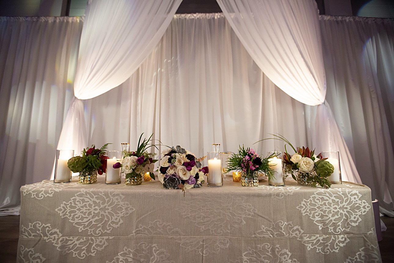 La mesa principal de una boda: cortinas blancas, flores y velas encendidas